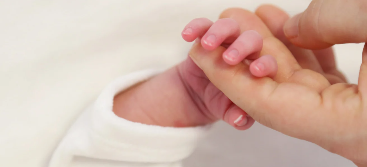 mujer sosteniendo mano de su bebe recien naciodo 001.png