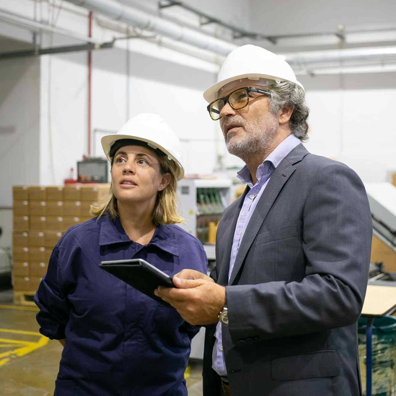 confident-bearded-supervisor-talking-with-female-plant-worker-holding-tablet.jpg