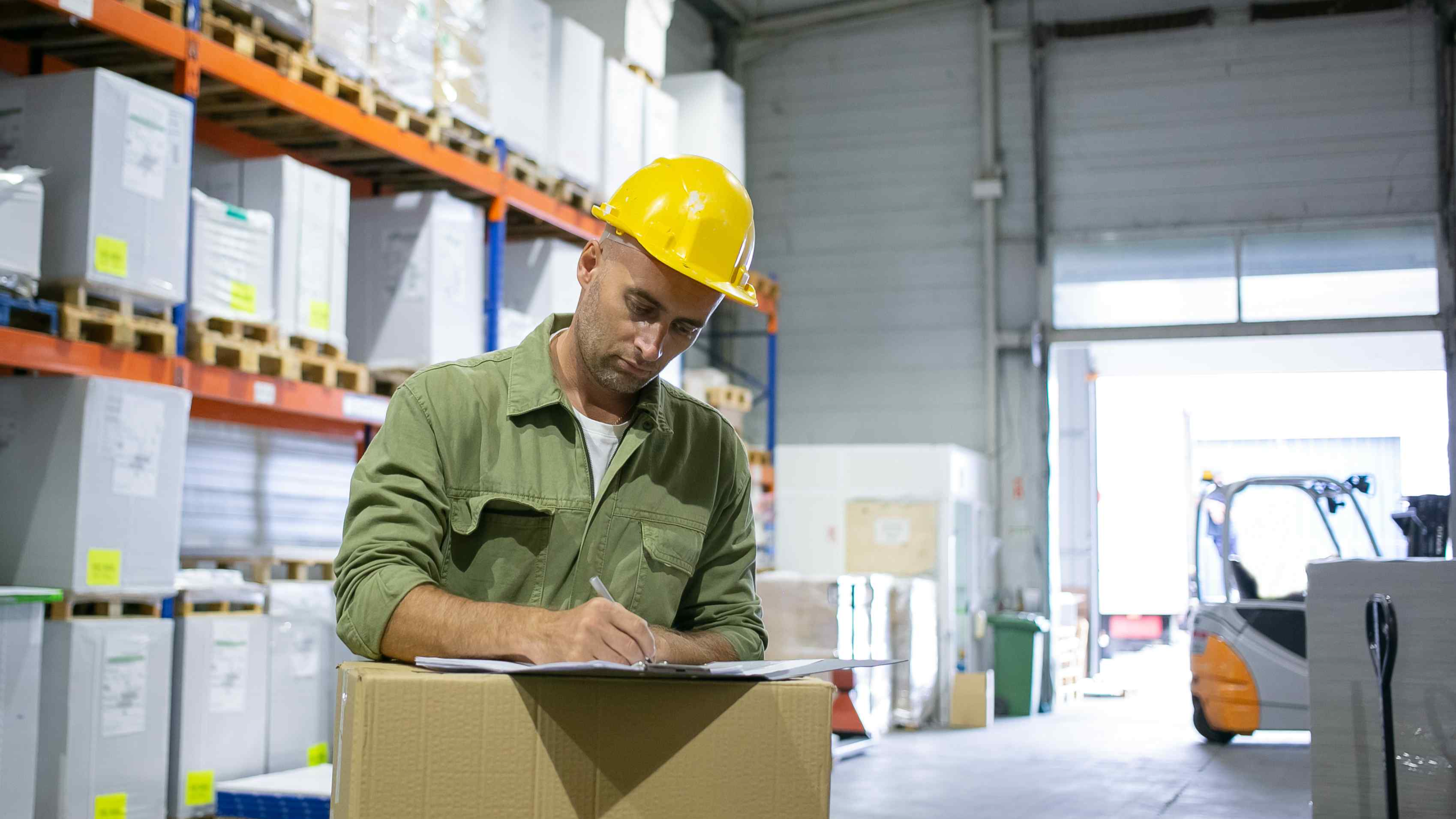 serious-male-logistic-engineer-hardhat-overall-standing-stack-boxes-completing-documents-copy-space-blue-collar-labor-concept.jpg
