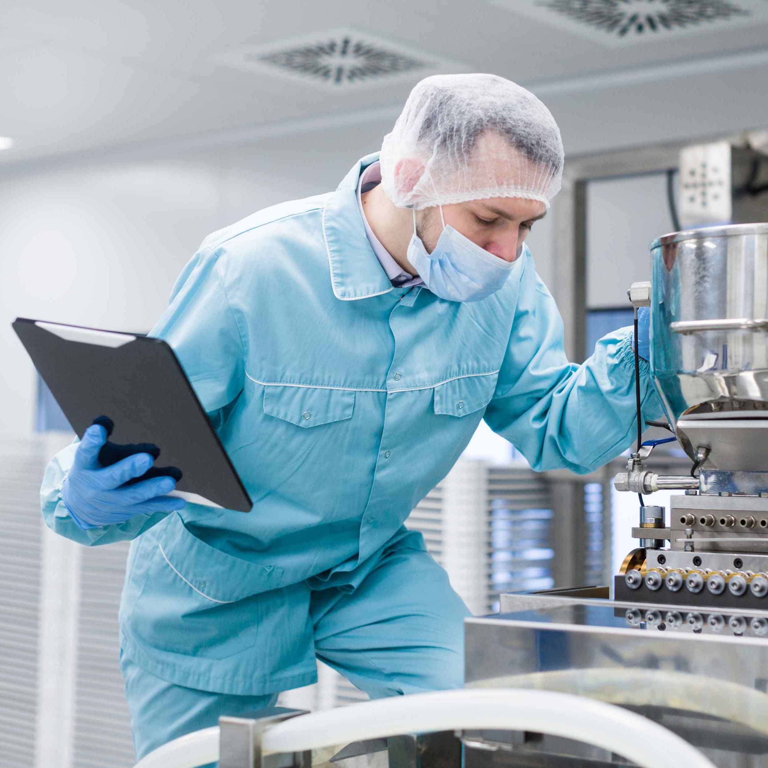 caucasian-scientist-man-blue-lab-suit-make-notes-about-big-steel-chromed-machine-with-tubes.jpg
